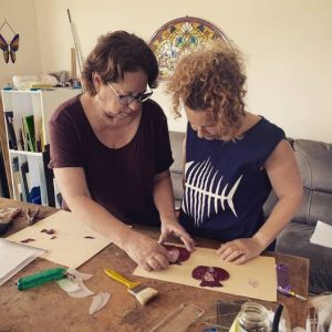 נירה מלמדת ומדגימה לתלמידה בסדנאות זכוכית